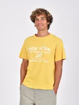 Remera de manga corta color mostaza con cuello redondo y estampado frontal en blanco que dice "NEW YORK PRO TENNIS CLASSIC september 15-23, 1994".