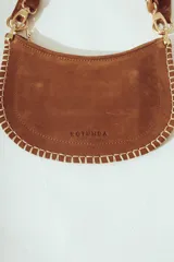 Cartera de hombro negra con forma de media luna, confeccionada en material con textura de pelo o cuero. Presenta costura decorativa gruesa en el borde y correa ajustable con herrajes metálicos plateados.