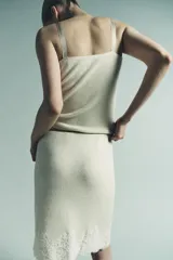 Top de punto color crema claro, corte recto y ajustado, con detalle de encaje floral bordado en el escote. Posee tirantes ajustables de color beige claro.