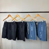 Bermuda de jean color negro con efecto desgastado y roturas, corte jogger arriba de la rodilla y cintura con cordón ajustable.