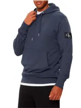 Buzo con capucha Calvin Klein color azul petróleo, con bolsillo tipo canguro, cordones ajustables y logo de la marca en la manga. Confeccionado en felpa de algodón.