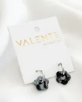 Aros colgantes con aro de acero plateado y dije de acrílico con forma de flor en tonos grises y negros.
