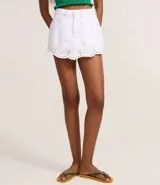 Short pollera corto de jeans blanco con bordados calados (cutout) y bajo festoneado. Presenta trabillas en la cintura y cierre tradicional.