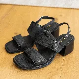 Sandalias negras de cuero vacuno con dos tiras anchas sobre el empeine y una tira fina trasera. Taco de madera de 5 cm y horma cuadrada.