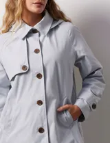 Gabardina color beige, impermeable, con abertura central con botones, bolsillos delanteros y capucha desmontable.