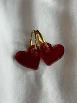 Par de aros colgantes con forma de corazón rojo brillante y argolla dorada.