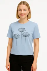 Remera celeste de algodón con cuello redondo y mangas cortas. Presenta un estampado de tres flores en color negro.