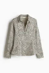 Camisa entallada de manga larga en tejido elástico de satén con estampado de leopardo. Modelo con cuello abierto, botonadura frontal y puños abotonados con abertura. Pinzas adelante y atrás para estilizar la figura.