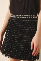 Minifalda negra de cuero gamuza con tachas bombé en la cintura y dos hileras de flecos con remaches metálicos plateados.
