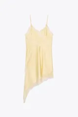 Vestido corto color amarillo pálido, de satén con tirantes finos, escote en V y bajo asimétrico con abertura. Presenta detalles de encaje en el escote, lateral y ruedo.