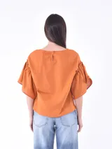 Blusa negra de mangas cortas con volados y escote redondo.