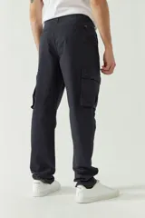 Pantalón cargo color beige para hombre, de corte recto, con bolsillos laterales y traseros. Se ajusta a la cintura con cinturón de cuero marrón.