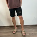 Bermuda de jean negra con corte skinny y roturas en las piernas.