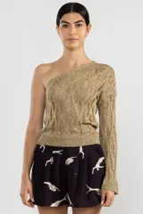 Top dorado de tejido calado, con un solo hombro y manga larga acampanada.