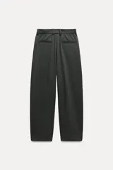 Pantalón de tiro medio color verde oscuro, confeccionado en hilatura con viscosa. Cintura con trabillas, bolsillos delanteros, pierna ancha y cierre frontal con cremallera, botón y gancho metálico.