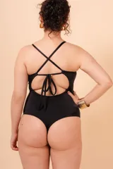 Malla entera negra con breteles finos, escote en V y detalle de aro dorado en el centro. Diseño colaless y espalda con tiras cruzadas. Confeccionada con tela que contiene fibra LYCRA® XTRA LIFE™.