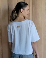 Remera negra con cuello redondo y mangas cortas, con detalle de pespuntes blancos en cuello, mangas, bolsillos frontales y ruedo.