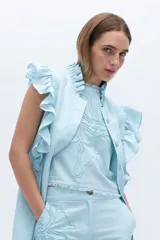 Blusa celeste de lino con bordado en relieve de formas orgánicas y terminaciones desflecadas.