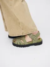 Sandalias romanas color verde oliva, con tiras entrecruzadas y hebilla lateral. Suela de goma negra con plataforma de 3cm. Fabricadas en cuero vacuno.