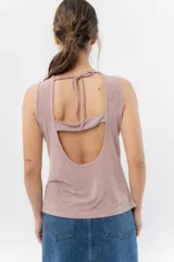 Musculosa color rosa metalizado, sin mangas, confeccionada en lino metalizado, con escote cerrado al frente y espalda abierta con lazo ajustable.