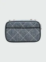 Bandolera Marc Jacobs modelo The Quilted Denim Softshot, confeccionada en denim azul acolchado con patrón de rombos. Presenta el logo Double J en metal plateado, correa de cuero y cadena, y cierre de cremallera doble.