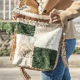 Cartera de cuero vacuno en combinación de colores verde, natural y oro, con manija corta y correa larga ajustable.