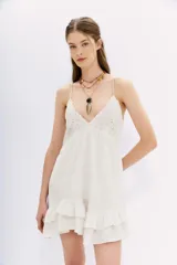 Vestido corto blanco de algodón con breteles finos, escote en V con detalle de bordado calado, espalda baja con elástico y volados en el ruedo.