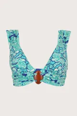 Top de bikini con estampado floral en tonos celeste, azul y blanco. Tiene breteles anchos con detalle de fruncido y accesorio decorativo de madera en el centro del busto.