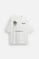 Camiseta blanca de corte holgado, cuello redondo y manga corta. Presenta estampados de textos combinados a contraste en delantero y espalda.