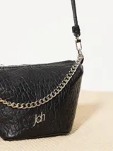 Bandolera negra de cuero vacuno con correa regulable y cadena metálica ornamental. Interior forrado en cuero vacuno con bolsillo interno con cierre.