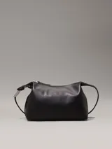 Bolso de hombro o cruzado de piel sintética negra, de forma rectangular y suave, con cierre superior de cremallera y correa ajustable con herrajes metálicos.