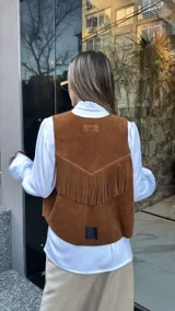 Chaleco marrón de cuero descarne con terminación en picos, tachas metálicas y flecos en la espalda.