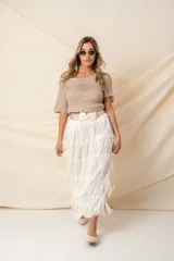 Pollera midi color vainilla, de gasa plisada con flecos y cintura elastizada.