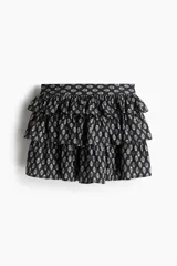 Minifalda negra con estampado floral blanco, cintura alta con elástico en la parte posterior y volados escalonados.