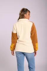 Campera de sherpa con cuello alto, cierre frontal y diseño combinado en bloques de color verde, beige y rosa.