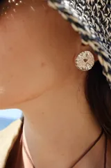 Aros tipo botón dorados con textura irregular que simula la superficie de un molusco.