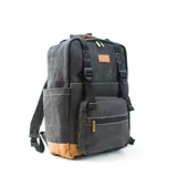 Mochila de tela canvas color gris con detalles en cuero marrón. Tiene compartimento principal con cierre, bolsillo frontal con cierre y bolsillos laterales. En el interior tiene espacio para mate, termo y porta notebook.