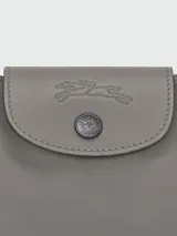 Bolso bandolera pequeño de cuero color gris con forma de media luna, cierre superior con cremallera y botón a presión, correa de cuero ajustable y extraíble, y herrajes plateados.