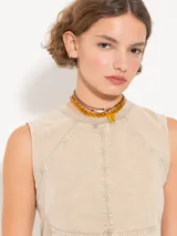 Top color beige confeccionado en tejido de algodón con cuello a la base y recortes de entalle.
