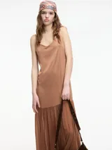 Vestido largo color marrón, con escote en V y breteles finos regulables. La falda tiene un corte con vuelo y una sección inferior de tela transparente.