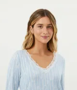 Conjunto de pijama largo de dos piezas en tejido de punto suave. La blusa es de manga larga con cuello en V y detalle de encaje. El pantalón es de corte recto con cintura elástica.