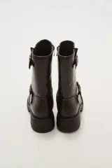 Bota corta de estilo motociclista color negro, con caña media y suela track gruesa. Presenta dos correas ajustables con hebillas metálicas plateadas alrededor del tobillo y la caña.