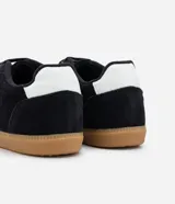 Championes negros de gamuza con suela de goma color caramelo y detalle blanco en el talón.