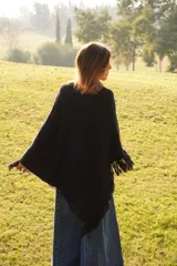 Poncho tejido en lana merino color crudo, con cuello alto y etiqueta de cuero con logo en la espalda.