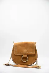 Bandolera color marrón de gamuza, con tachas doradas y herraje circular dorado en el frente.