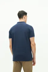 Polo color beige con textura, corte regular, logo estampado en el pecho y mangas cortas con ribete blanco.