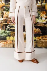 Pantalón de vestir color manteca con corte acampanado y detalle de ribetes marrones en los laterales.