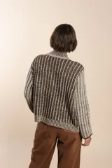 Cárdigan tejido a rayas verticales marrones y beige, con cuello esmoquin, cierre frontal con botones y corte holgado. Tejido en 100% lana fina sin teñir.