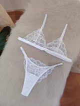 Conjunto de lencería blanco de encaje, compuesto por un bralette triangular con breteles regulables y una tanga regulable de corte less con entrepierna de algodón.