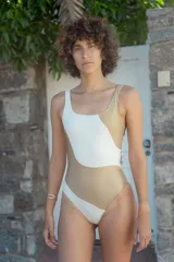 Traje de baño enterizo color dorado y blanco con diseño asimétrico.